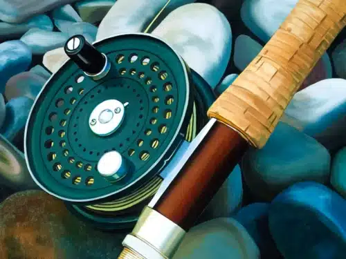 Close-up of a green fishing reel with a brown wooden rod handle resting on smooth blue and gray stones.